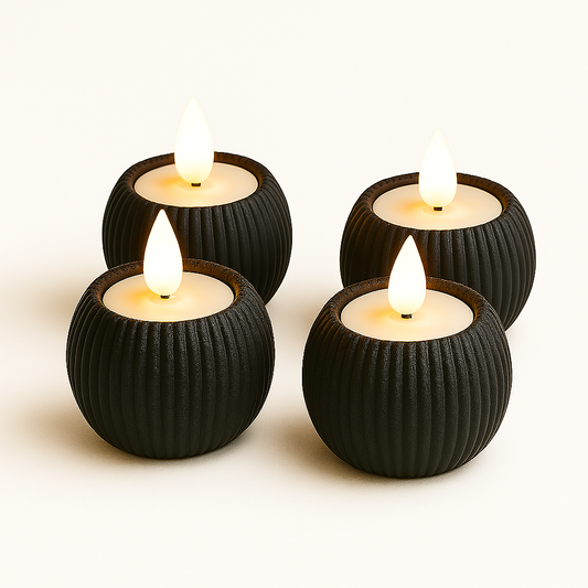 Four black ribbed candle holders with lit candles on a white background