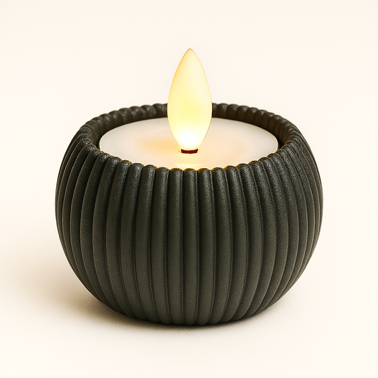 Black ribbed candle holder with a lit candle on a white background